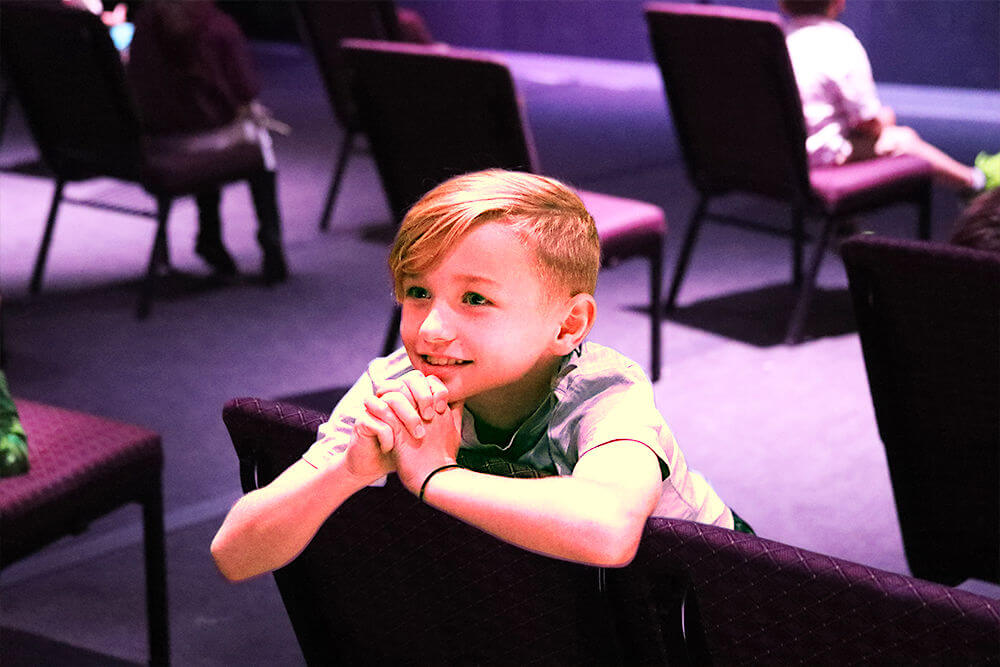 kidslife - boy sitting in chair in prayer